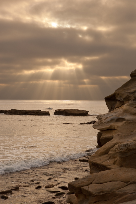 paddle by ray.jpg :: A lone stand up paddler is backdropped by the setting sun's rays driving through the clouds. (A2:3) (LE5k)