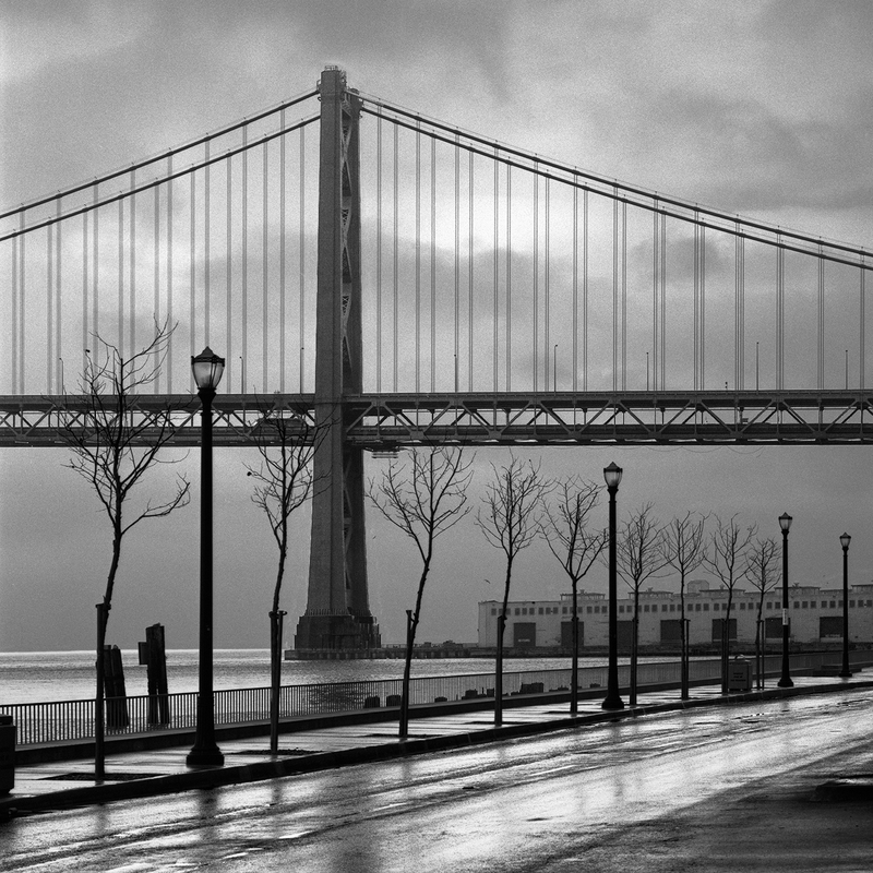 San Francisco -- Bay Bridge in the Rain(1).jpg :: The San Francisco Bay Bridge before the Embarcadero was remodeled. Exposed at 8:30 AM on February 15, 1986 through a 150 mm lens on Hasselblad 500 CM using Kodak Tri-X film at f45 and 1/15 of a second with a deep red filter.    To see a rectangular version of this image, click on \