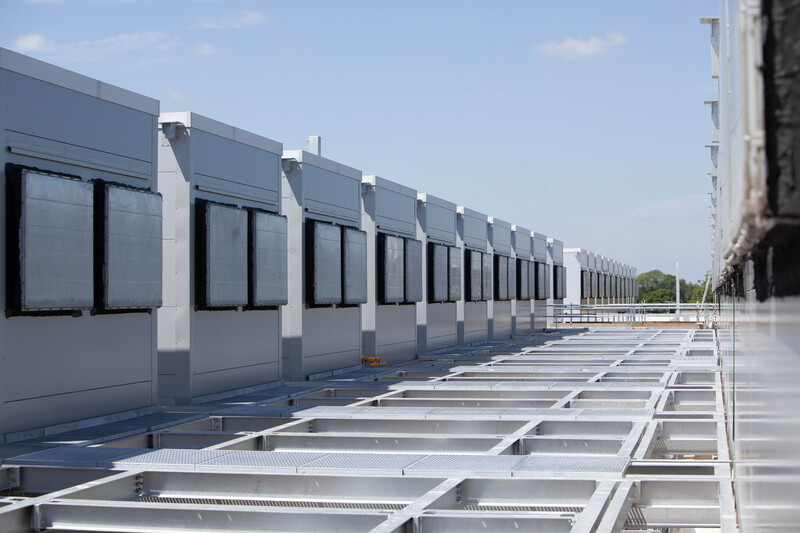Modular Data Centre Assembly  Industrial Scale.jpg :: Showcasing the deployment of modular data centre containment units. This symmetrical exterior view highlights the rapid deployment and architectural repeat typical of modern data facility design.