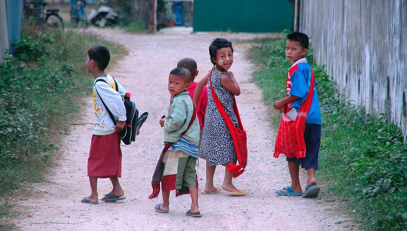 CHILDREN OF MAE SOT.jpg :: VILLAGE OF MAE SOT.  TAK PROVINCE, THAILAND.   A group of children work their way home from school along unpaved rural streets of Mae Sot 