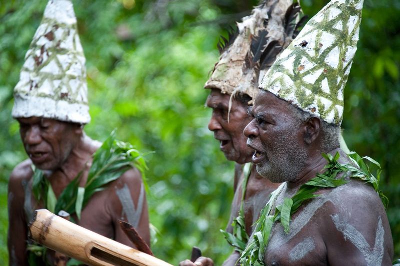 DANCE OF THE ARRIVAL.jpg :: VILLAGE OF LUTES.  ISLAND OF ULEVEO, MASKELYNE ISLAND GROUP, VANUATU.    Villagers from Lutes recreate and pay homage to ancestors who braved a thousand miles of open sea to arrive in Vanuatu and the Maskelyne Islands 4,000 years ago. The dancers included village elders and young men who brought incredible power and emotion to the scene. All of the dancers used brightly colored paddles while a single dancer used a coconut to simulate bailing of seawater during the long voyage. 


