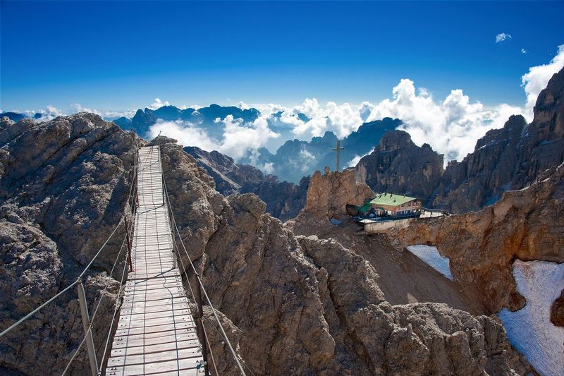 REFUGIO LORENZI.jpg :: Cortina, Italy.     
The 27m suspension bridge at Regugio Lorenzi (2,919m) marks the beginning of the Ivano Dibona via ferrata in the awe inspiring Italian Dolomite mountain range. These routes were used by Italian soldiers in WWI to guard the vertical passes from invasion by Austrian forces. Over 60,000 troops lost their lives defending the Dolomites.