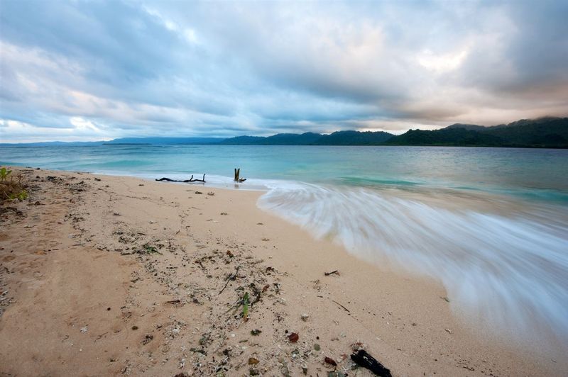 SUNRISE AT LEUMANANG.jpg :: LEUMANANG ISLAND - UMBEB BAY.  MOLECULE ISLAND, VANUATU. 
Lateral waves slide across the north tip of uninhabited Leumanang Island. This island and its twin sister, Varo Island, are nestled in the remarkably beautiful Umbeb Bay. Both islands are surrounded by extensive pristine coral reefs, intense clear blue water, and are home to thick jungle interiors. We landed to camp overnight and seek protection from heavy surf and storms passing through.