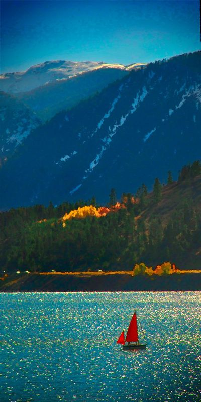 RedSail.jpg :: In the mountains of Colorado there is this lake, I wish I could remember its name, someone may know by the mountain in the background - please let me know and I can name it. beautiful red sail on a cyan lake, in front of evergreens, with a couple of yellow cypress, blue mountains. Just missing a little obvious magenta and we would have a complete color pallet.