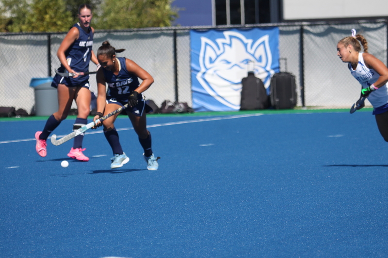 Saint Louis University (SLU) Field Hockey vs UC Davis 2025 L.jpg :: SLU Field Hockey vs University of California Davis at the SLU Field Hockey Complex - Women's Field Hockey - The standard field size for field hockey is 300 feet (100 meters) long and 167 feet wide. A field hockey field's boundaries are marked with the end lines going across the width and sidelines going across the length. - The field is divided into quarters by four lines. The 25-yard line are 25 yards from each end line, and the center line runs through the middle of the field. The goalposts are 12 feet wide, 7 feet tall, and 4 feet deep. Each goal post is situated in the center of each end line. - The Striking Circle is a Semi-Circle with a radius of around 48 feet surrounding each goal. - There are always 22 players on the field, 11 from each team. Each team has a goalkeeper and 10 fielders.