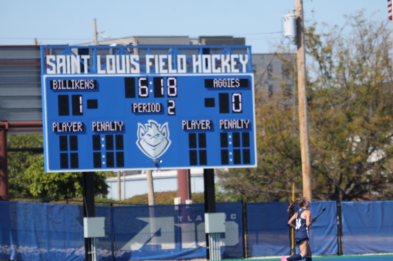 Saint Louis University (SLU) Field Hockey vs UC Davis 2025 LI.jpg :: SLU Field Hockey vs University of California Davis at the SLU Field Hockey Complex - Women's Field Hockey - The standard field size for field hockey is 300 feet (100 meters) long and 167 feet wide. A field hockey field's boundaries are marked with the end lines going across the width and sidelines going across the length. - The field is divided into quarters by four lines. The 25-yard line are 25 yards from each end line, and the center line runs through the middle of the field. The goalposts are 12 feet wide, 7 feet tall, and 4 feet deep. Each goal post is situated in the center of each end line. - The Striking Circle is a Semi-Circle with a radius of around 48 feet surrounding each goal. - There are always 22 players on the field, 11 from each team. Each team has a goalkeeper and 10 fielders.