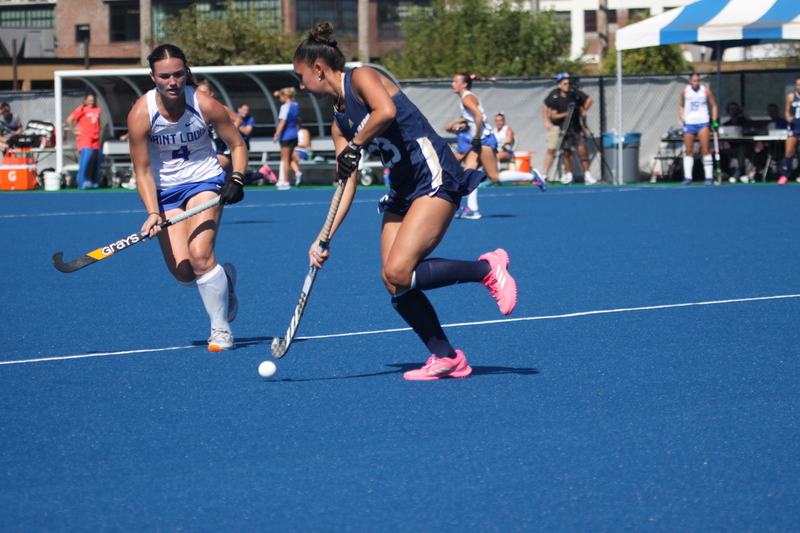 Saint Louis University (SLU) Field Hockey vs UC Davis 2025 LII.jpg :: SLU Field Hockey vs University of California Davis at the SLU Field Hockey Complex - Women's Field Hockey - The standard field size for field hockey is 300 feet (100 meters) long and 167 feet wide. A field hockey field's boundaries are marked with the end lines going across the width and sidelines going across the length. - The field is divided into quarters by four lines. The 25-yard line are 25 yards from each end line, and the center line runs through the middle of the field. The goalposts are 12 feet wide, 7 feet tall, and 4 feet deep. Each goal post is situated in the center of each end line. - The Striking Circle is a Semi-Circle with a radius of around 48 feet surrounding each goal. - There are always 22 players on the field, 11 from each team. Each team has a goalkeeper and 10 fielders.