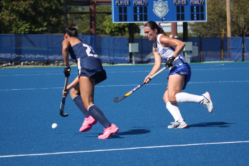 Saint Louis University (SLU) Field Hockey vs UC Davis 2025 LV.jpg :: SLU Field Hockey vs University of California Davis at the SLU Field Hockey Complex - Women's Field Hockey - The standard field size for field hockey is 300 feet (100 meters) long and 167 feet wide. A field hockey field's boundaries are marked with the end lines going across the width and sidelines going across the length. - The field is divided into quarters by four lines. The 25-yard line are 25 yards from each end line, and the center line runs through the middle of the field. The goalposts are 12 feet wide, 7 feet tall, and 4 feet deep. Each goal post is situated in the center of each end line. - The Striking Circle is a Semi-Circle with a radius of around 48 feet surrounding each goal. - There are always 22 players on the field, 11 from each team. Each team has a goalkeeper and 10 fielders.