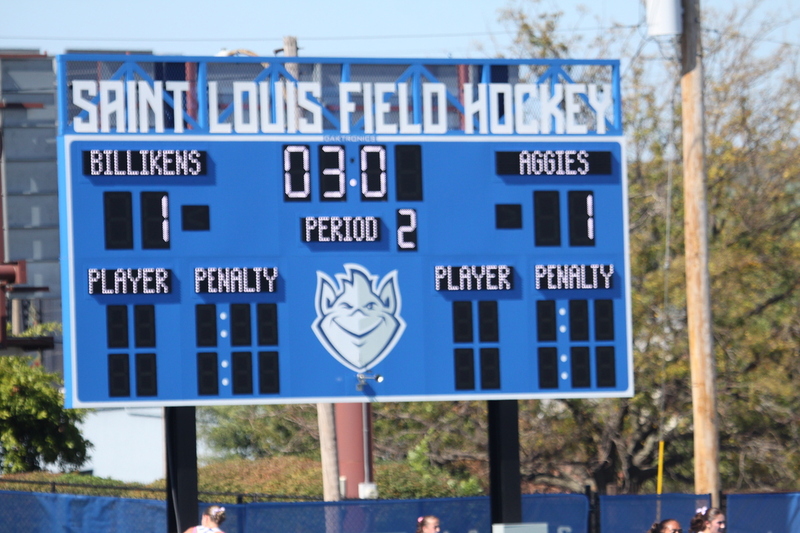 Saint Louis University (SLU) Field Hockey vs UC Davis 2025 LVII.jpg :: SLU Field Hockey vs University of California Davis at the SLU Field Hockey Complex - Women's Field Hockey - The standard field size for field hockey is 300 feet (100 meters) long and 167 feet wide. A field hockey field's boundaries are marked with the end lines going across the width and sidelines going across the length. - The field is divided into quarters by four lines. The 25-yard line are 25 yards from each end line, and the center line runs through the middle of the field. The goalposts are 12 feet wide, 7 feet tall, and 4 feet deep. Each goal post is situated in the center of each end line. - The Striking Circle is a Semi-Circle with a radius of around 48 feet surrounding each goal. - There are always 22 players on the field, 11 from each team. Each team has a goalkeeper and 10 fielders.
