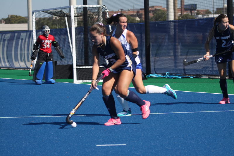 Saint Louis University (SLU) Field Hockey vs UC Davis 2025 XXII.jpg :: SLU Field Hockey vs University of California Davis at the SLU Field Hockey Complex - Women's Field Hockey - The standard field size for field hockey is 300 feet (100 meters) long and 167 feet wide. A field hockey field's boundaries are marked with the end lines going across the width and sidelines going across the length. - The field is divided into quarters by four lines. The 25-yard line are 25 yards from each end line, and the center line runs through the middle of the field. The goalposts are 12 feet wide, 7 feet tall, and 4 feet deep. Each goal post is situated in the center of each end line. - The Striking Circle is a Semi-Circle with a radius of around 48 feet surrounding each goal. - There are always 22 players on the field, 11 from each team. Each team has a goalkeeper and 10 fielders.