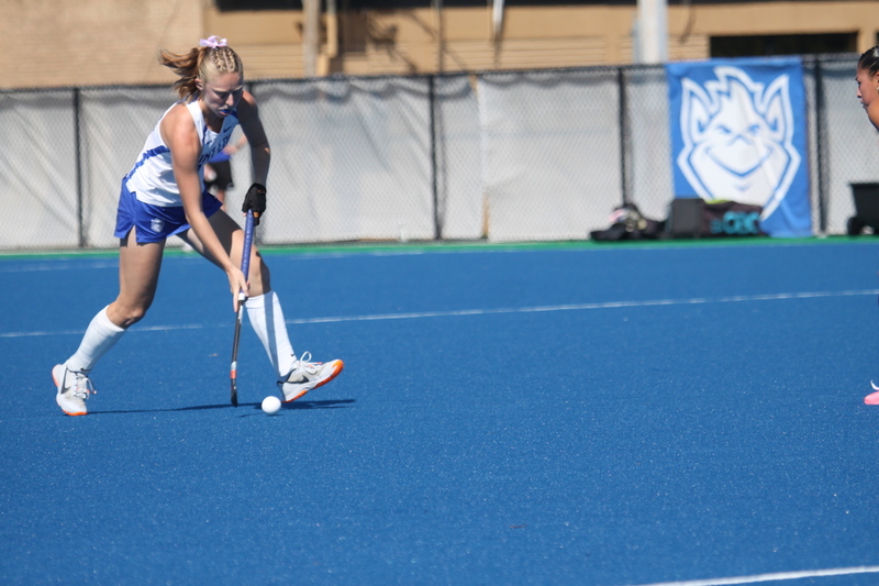 Saint Louis University (SLU) Field Hockey vs UC Davis 2025 XXXII.jpg :: SLU Field Hockey vs University of California Davis at the SLU Field Hockey Complex - Women's Field Hockey - The standard field size for field hockey is 300 feet (100 meters) long and 167 feet wide. A field hockey field's boundaries are marked with the end lines going across the width and sidelines going across the length. - The field is divided into quarters by four lines. The 25-yard line are 25 yards from each end line, and the center line runs through the middle of the field. The goalposts are 12 feet wide, 7 feet tall, and 4 feet deep. Each goal post is situated in the center of each end line. - The Striking Circle is a Semi-Circle with a radius of around 48 feet surrounding each goal. - There are always 22 players on the field, 11 from each team. Each team has a goalkeeper and 10 fielders.