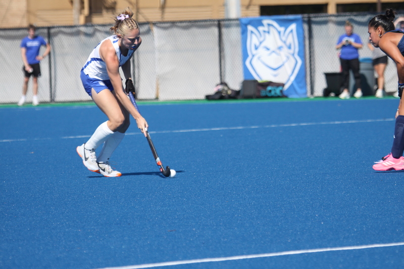 Saint Louis University (SLU) Field Hockey vs UC Davis 2025 XXXIII.jpg :: SLU Field Hockey vs University of California Davis at the SLU Field Hockey Complex - Women's Field Hockey - The standard field size for field hockey is 300 feet (100 meters) long and 167 feet wide. A field hockey field's boundaries are marked with the end lines going across the width and sidelines going across the length. - The field is divided into quarters by four lines. The 25-yard line are 25 yards from each end line, and the center line runs through the middle of the field. The goalposts are 12 feet wide, 7 feet tall, and 4 feet deep. Each goal post is situated in the center of each end line. - The Striking Circle is a Semi-Circle with a radius of around 48 feet surrounding each goal. - There are always 22 players on the field, 11 from each team. Each team has a goalkeeper and 10 fielders.