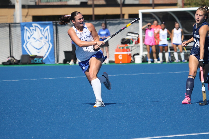 Saint Louis University (SLU) Field Hockey vs UC Davis 2025 XXXV.jpg :: SLU Field Hockey vs University of California Davis at the SLU Field Hockey Complex - Women's Field Hockey - The standard field size for field hockey is 300 feet (100 meters) long and 167 feet wide. A field hockey field's boundaries are marked with the end lines going across the width and sidelines going across the length. - The field is divided into quarters by four lines. The 25-yard line are 25 yards from each end line, and the center line runs through the middle of the field. The goalposts are 12 feet wide, 7 feet tall, and 4 feet deep. Each goal post is situated in the center of each end line. - The Striking Circle is a Semi-Circle with a radius of around 48 feet surrounding each goal. - There are always 22 players on the field, 11 from each team. Each team has a goalkeeper and 10 fielders.