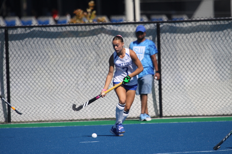Saint Louis University (SLU) Field Hockey vs UC Davis 2025 XXXVI.jpg :: SLU Field Hockey vs University of California Davis at the SLU Field Hockey Complex - Women's Field Hockey - The standard field size for field hockey is 300 feet (100 meters) long and 167 feet wide. A field hockey field's boundaries are marked with the end lines going across the width and sidelines going across the length. - The field is divided into quarters by four lines. The 25-yard line are 25 yards from each end line, and the center line runs through the middle of the field. The goalposts are 12 feet wide, 7 feet tall, and 4 feet deep. Each goal post is situated in the center of each end line. - The Striking Circle is a Semi-Circle with a radius of around 48 feet surrounding each goal. - There are always 22 players on the field, 11 from each team. Each team has a goalkeeper and 10 fielders.