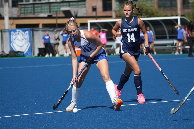Saint Louis University (SLU) Field Hockey vs UC Davis 2025 XXXVIII.jpg :: SLU Field Hockey vs University of California Davis at the SLU Field Hockey Complex - Women's Field Hockey - The standard field size for field hockey is 300 feet (100 meters) long and 167 feet wide. A field hockey field's boundaries are marked with the end lines going across the width and sidelines going across the length. - The field is divided into quarters by four lines. The 25-yard line are 25 yards from each end line, and the center line runs through the middle of the field. The goalposts are 12 feet wide, 7 feet tall, and 4 feet deep. Each goal post is situated in the center of each end line. - The Striking Circle is a Semi-Circle with a radius of around 48 feet surrounding each goal. - There are always 22 players on the field, 11 from each team. Each team has a goalkeeper and 10 fielders.
