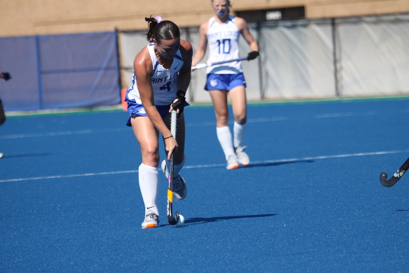 Saint Louis University (SLU) Field Hockey vs UC Davis 2025 XXXXII.jpg :: SLU Field Hockey vs University of California Davis at the SLU Field Hockey Complex - Women's Field Hockey - The standard field size for field hockey is 300 feet (100 meters) long and 167 feet wide. A field hockey field's boundaries are marked with the end lines going across the width and sidelines going across the length. - The field is divided into quarters by four lines. The 25-yard line are 25 yards from each end line, and the center line runs through the middle of the field. The goalposts are 12 feet wide, 7 feet tall, and 4 feet deep. Each goal post is situated in the center of each end line. - The Striking Circle is a Semi-Circle with a radius of around 48 feet surrounding each goal. - There are always 22 players on the field, 11 from each team. Each team has a goalkeeper and 10 fielders.