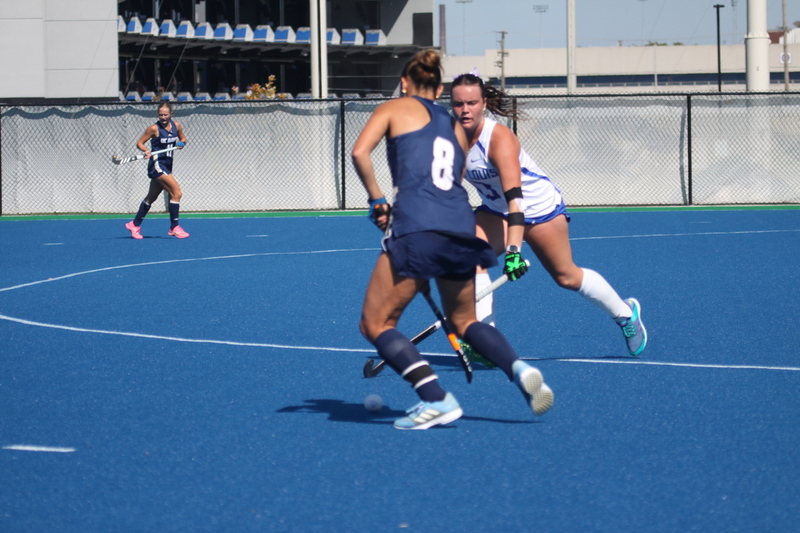 Saint Louis University (SLU) Field Hockey vs UC Davis 2025 XXXXIX.jpg :: SLU Field Hockey vs University of California Davis at the SLU Field Hockey Complex - Women's Field Hockey - The standard field size for field hockey is 300 feet (100 meters) long and 167 feet wide. A field hockey field's boundaries are marked with the end lines going across the width and sidelines going across the length. - The field is divided into quarters by four lines. The 25-yard line are 25 yards from each end line, and the center line runs through the middle of the field. The goalposts are 12 feet wide, 7 feet tall, and 4 feet deep. Each goal post is situated in the center of each end line. - The Striking Circle is a Semi-Circle with a radius of around 48 feet surrounding each goal. - There are always 22 players on the field, 11 from each team. Each team has a goalkeeper and 10 fielders.
