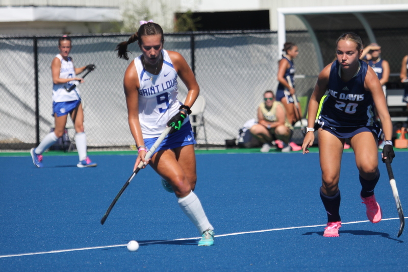 Saint Louis University (SLU) Field Hockey vs UC Davis 2025 XXXXVI.jpg :: SLU Field Hockey vs University of California Davis at the SLU Field Hockey Complex - Women's Field Hockey - The standard field size for field hockey is 300 feet (100 meters) long and 167 feet wide. A field hockey field's boundaries are marked with the end lines going across the width and sidelines going across the length. - The field is divided into quarters by four lines. The 25-yard line are 25 yards from each end line, and the center line runs through the middle of the field. The goalposts are 12 feet wide, 7 feet tall, and 4 feet deep. Each goal post is situated in the center of each end line. - The Striking Circle is a Semi-Circle with a radius of around 48 feet surrounding each goal. - There are always 22 players on the field, 11 from each team. Each team has a goalkeeper and 10 fielders.