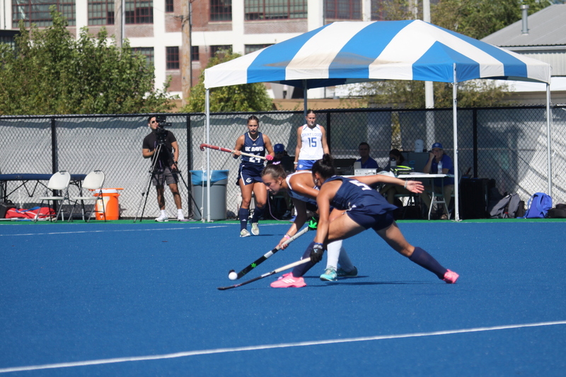 Saint Louis University (SLU) Field Hockey vs UC Davis 2025 XXXXVII.jpg :: SLU Field Hockey vs University of California Davis at the SLU Field Hockey Complex - Women's Field Hockey - The standard field size for field hockey is 300 feet (100 meters) long and 167 feet wide. A field hockey field's boundaries are marked with the end lines going across the width and sidelines going across the length. - The field is divided into quarters by four lines. The 25-yard line are 25 yards from each end line, and the center line runs through the middle of the field. The goalposts are 12 feet wide, 7 feet tall, and 4 feet deep. Each goal post is situated in the center of each end line. - The Striking Circle is a Semi-Circle with a radius of around 48 feet surrounding each goal. - There are always 22 players on the field, 11 from each team. Each team has a goalkeeper and 10 fielders.
