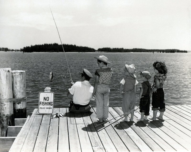 MISCELLANEOUS 9-56 police officer fishing by no fishing sign as children watch c. 1957..jpg