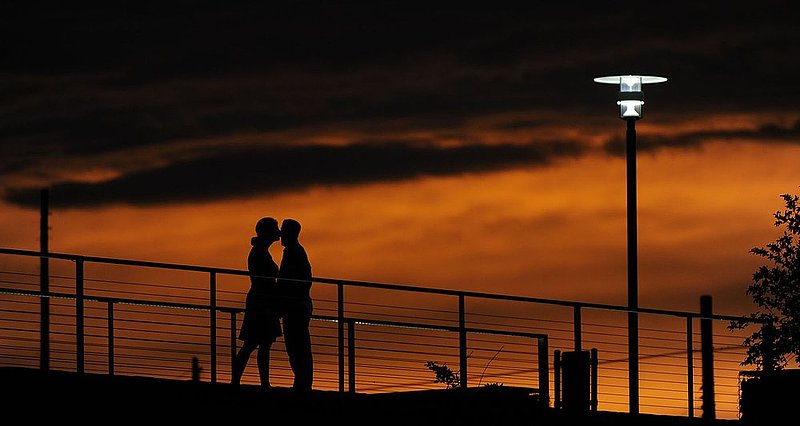 ALBIN101 SUNSET  3.jpg :: A couple share a kiss on a walkway at Railroad Park Friday June 24, 2011 in Birmingham, Ala as the sun sets after a line of thunder storms moved though the metro area clearing skies and lowering the temperature.  (AP Photo/The Birmingham News, Hal Yeager)