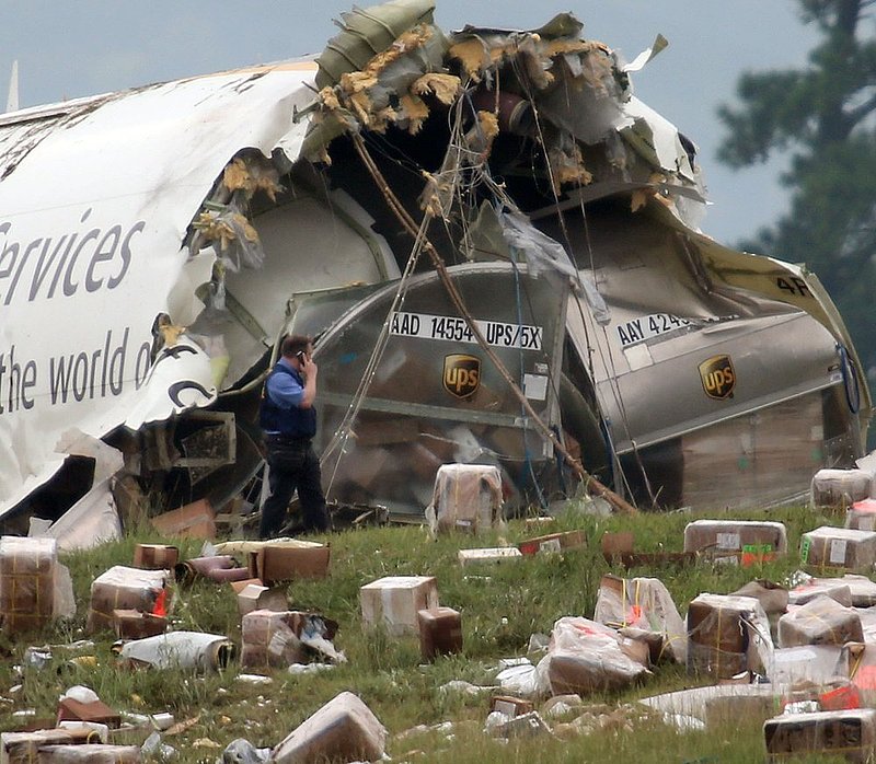 ALHY113.jpg :: A postal Inspector officer looks over the debris of a UPS A300 cargo plane after it crashed on approach at Birmingham-Shuttlesworth International Airport  this morning Wednesday August 14,  2013 in Birmingham, Ala. (AP Photo/Hal Yeager)