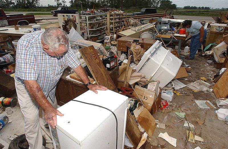 DENNIS AFTERMATH_003.jpg :: DENNIS AFTERMATH--Hurricane Dennis left a path of destruction as it moved through south Alabama. Harvey Burkett takes a moment to gather himself as he was describing the destruction to his brother in law Lee Seale's business, Builders and Hardware Supply on highway 31 in Atmore. Burkett along with Seale's sister Lois Cramer, background, were helping to salvage what they could.  News staff/Hal Yeager reporter/Blackledge