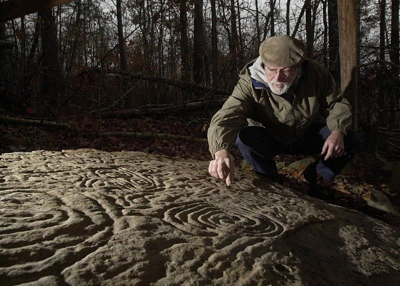 HIEROGLYPHICS73.jpg :: Archelolgist Bart Henson, Huntsville, examines a huge sandstone Petroglyph located in a field behind a farm house in Colbert county. The stone is adorned with spirals, snakes and crosses carved by Mississippian period indians, 1,000AD to 1,500AD.