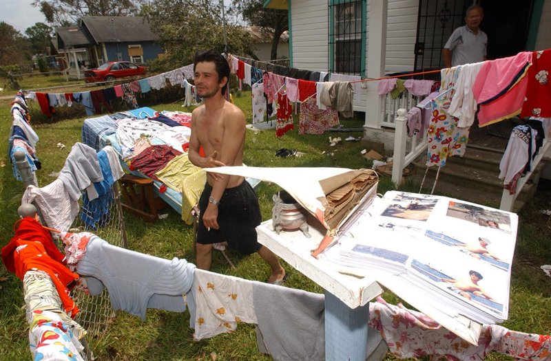 HURRICANE KATRINA_018.jpg :: HURRICANE KATRINA--Duoc Van Nyungin and Huong Locan of Bayou La Batre hung clothes out all over the property after the house was flooded with 8 feet of water. News staff/Hal Yeager  reporter/Chandler