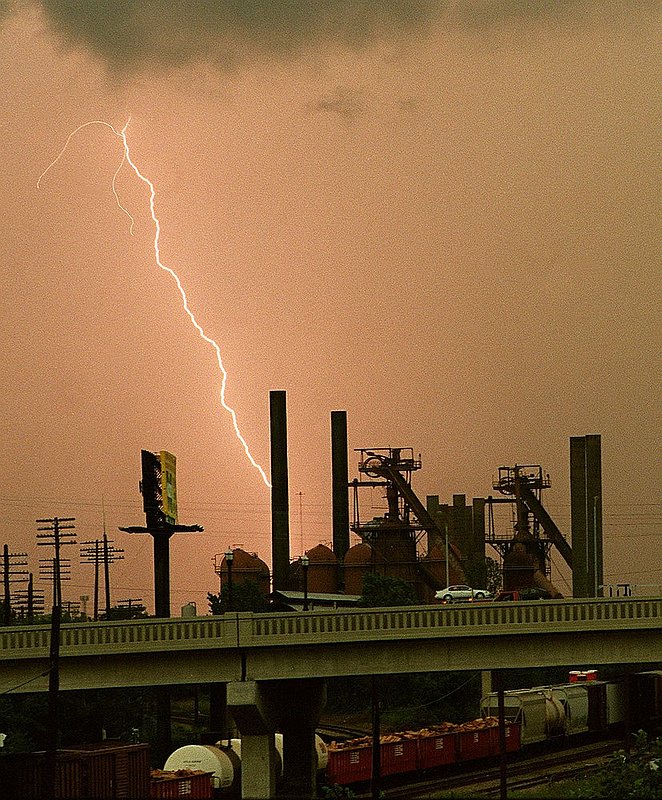 LIGHTNING_001.jpg :: A LIGHTNING BOLT SEEMS TO STRIKE A STACK AT SLOSS FURNACE AS AN EVENING RUSH-HOUR STORM PASSES OVER DOWNTOWN. YEAGER PHOTO  97-3386