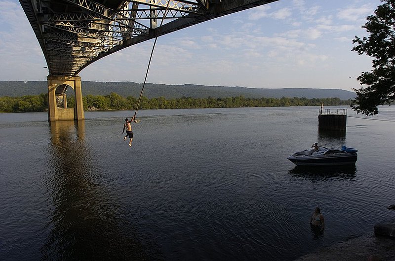 ROPE SWING2.jpg :: ROPE SWING----While inspecting the John Snodgrass bridge over the Tennessee River near Stevenson, Ala.,  workers discovered this rope swing tied beneath the girders. Four of the workers, Robert Miller, Pittsburg Pa., Cherish Miller, Pittsburg, Amber Rowley, Stubbeville, Ohio, and Dean Peryea, Stubbeville, took turns taking a cooling plunge into the river after a long hot humid day of work. They will be in the state about two more weeks until the inspection work is complete. Amber and Dean watch from their boat and Cherish watches from the water as Robert swings. News staff/Hal Yeager