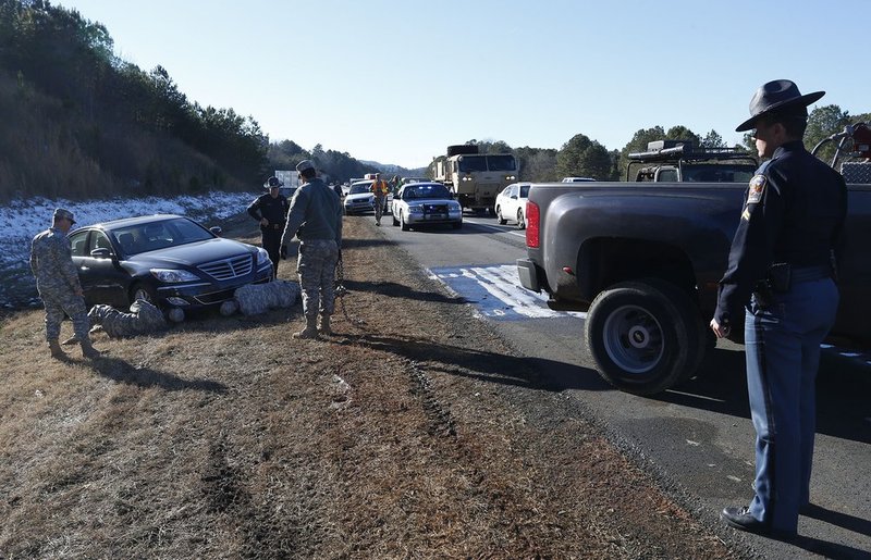 WINTER WEATHER ALHY112                                 .jpg :: An Alabama state trooper watches as Alabama Army National Guard troops assist Tommy Holmes with his stuck vehicle on interstate 20 Thursday Jan. 30,  2014 in Leeds,  Ala. The south woke up to more freezing temperatures but officials are hoping for a thaw and relief from the icy conditions. (AP Photo/Hal Yeager)