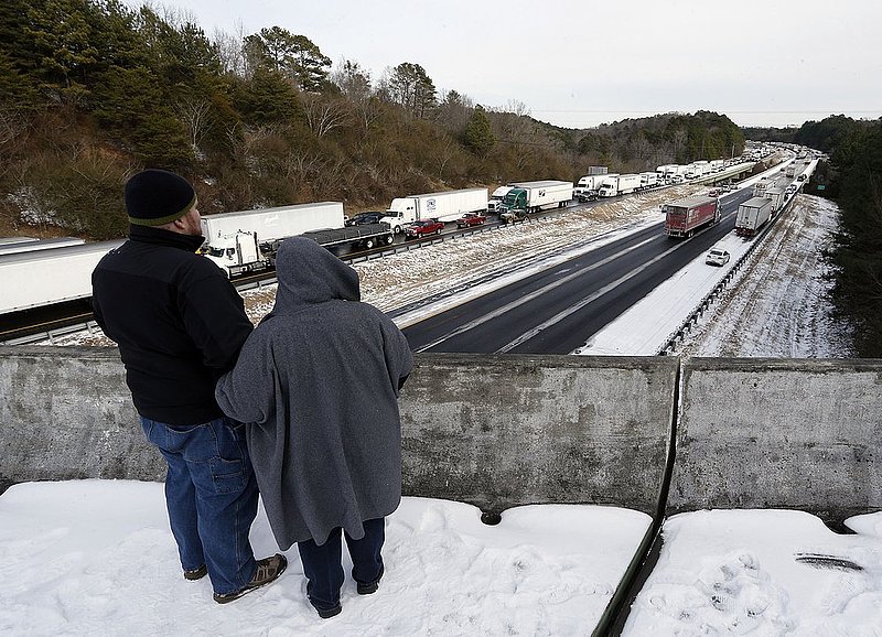 WINTER WEATHER ALHY119         .jpg :: Mike and Brooke Streufert watch stranded interstate 20 traffic from an overpass near their house Wednesday January 29,  2014 in Leeds,  Ala. Officials worked today to clear hundreds of abandoned vehicles left during yesterday's snow storm.  (AP Photo/Hal Yeager)