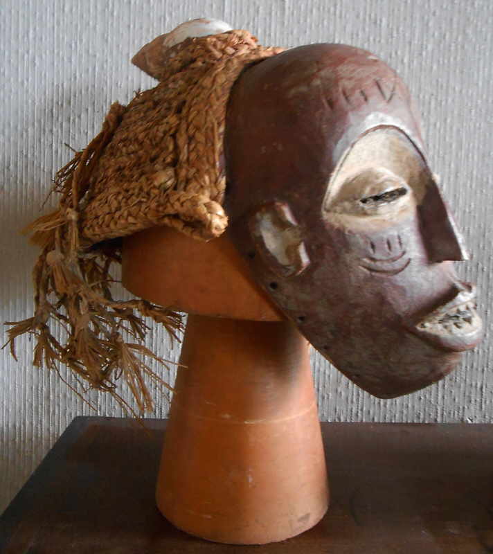 African CHOKWE Pwo Female Mask.jpg :: This fine mask is from Angola c. 1900.  Its delicate features represents the Chokwe founding female ancestor.  Such masks celebrate the conclusion of the initiation process marking the transition from childhood to adulthood. 
The elegant reserve of the features, with slit eyes under arching brows, tiny nose and flattened lips exposing small teeth are typical, as is an elaborate grass hair. The straight lines under the eyes represent tears of pride and sorrow shed by mothers as their sons, becoming adults, lose the intimate connection of mother and child.
This is a particularly rare example because it includes a Giant African Land Snail shell woven into the grass fibre on top of the mask.  This example is very similar to the one at the Metropolitan Museum collection in New York.
