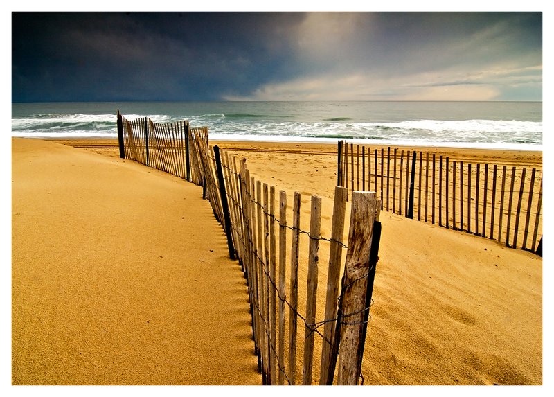 snowfence-storm.jpg :: Snowfencing on a winter beach with storm clouds building in the distance.