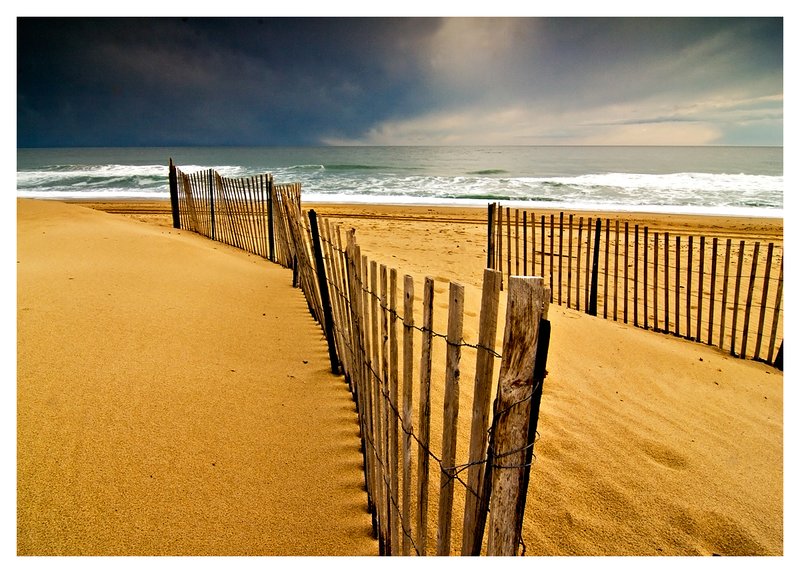 snowfence-storm.jpg :: Snowfencing on a winter beach with storm clouds building in the distance.