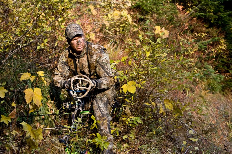 ©TC-Bowhunter-D90010-00609.jpg :: Bowhunter (wearing Advantage AP Brown Camo carrying a Hoyt Compound Bow) crouched down in deadfall and brush rattling for whitetails