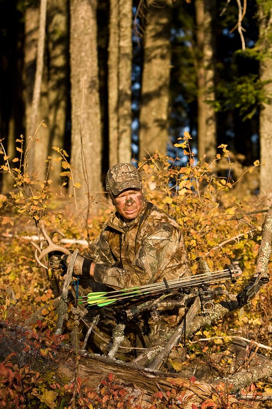 ©TC-Bowhunter-D90010-00630.jpg :: Bowhunter (wearing Advantage AP Brown Camo carrying a Hoyt Compound Bow) crouched down in deadfall and brush rattling for whitetails