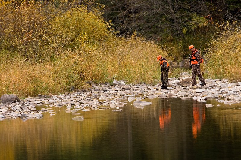 ©TC-Hunter Parent Child-D89995-00021.jpg :: Father wearing Advantage Max 4 camo w/florescent orange vest & hat hunts with his son wearing Realtree Brown camo and florescent orange vest/hat hunt along a river backwater in fall colors