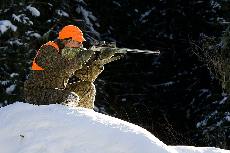 ©TC-Muzzleloader Hunter In Snow-D90008-00056.jpg :: Muzzleloader hunter in snow wearing Filson Wool Clothes in Advantage Timber Camoflage with florescent orange vest and hat shooting CVA Muzzleloader topped with Nikon Omega Muzzleloader scope