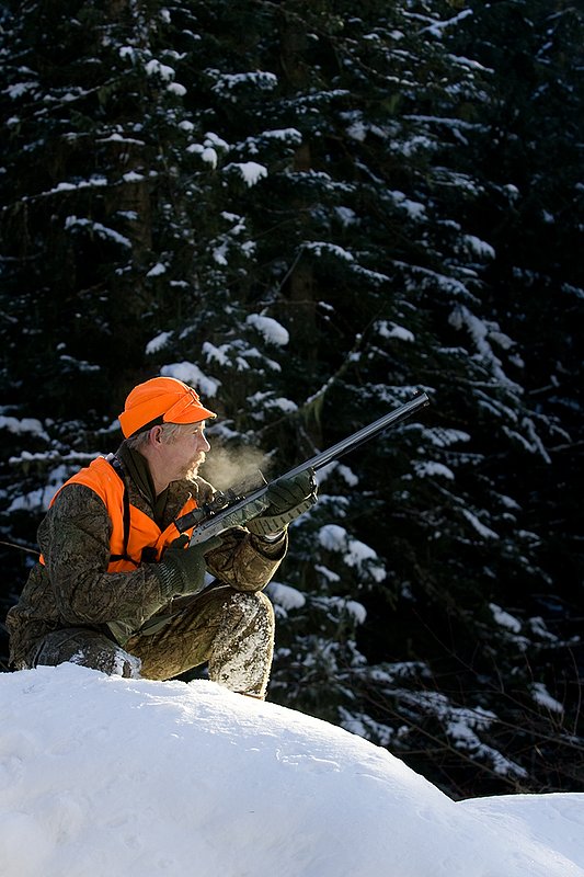 ©TC-Muzzleloader Hunter In Snow-D90008-00070.jpg :: Muzzleloader hunter in snow wearing Filson Wool Clothes in Advantage Timber Camoflage with florescent orange vest and hat shooting CVA Muzzleloader topped with Nikon Omega Muzzleloader scope