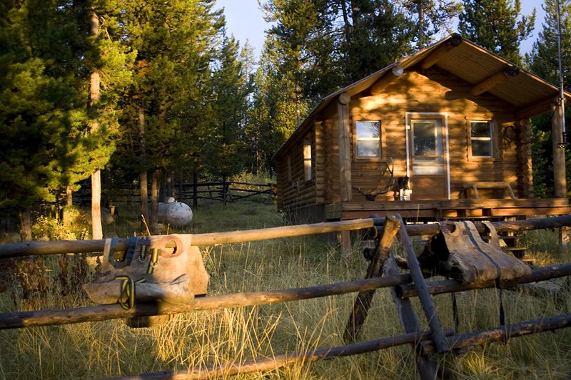 ©TC_Hunting Camps-D80003-101.jpg :: Elk Camp, cabin in woods, with elk rack on porch, panniers for carrying elk quarters, Peet shoe dryer, drying boots after the hunt,