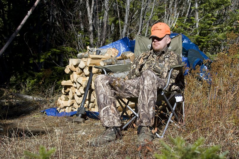 ©TC_Hunting Camps-D80003-139.jpg :: Hunter sitting in lawn chair taking nap in front of wood pile in midday sun, resting from morning of elk hunting
