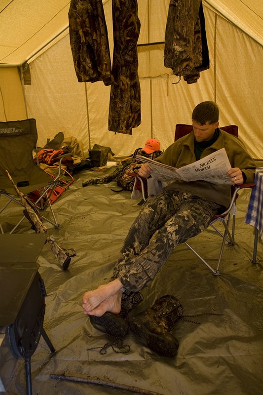 ©TC_Hunting Camps-D80003-144.jpg :: Hunter sitting on chair inside wall tent, getting warm and drying off after a day of hunting elk