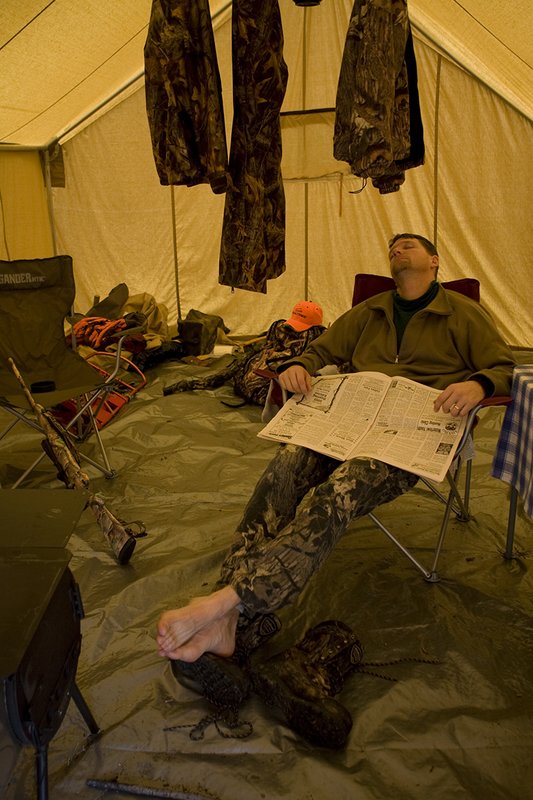 ©TC_Hunting Camps-D80003-145.jpg :: Hunter sitting on chair inside wall tent, getting warm and drying off after a day of hunting elk