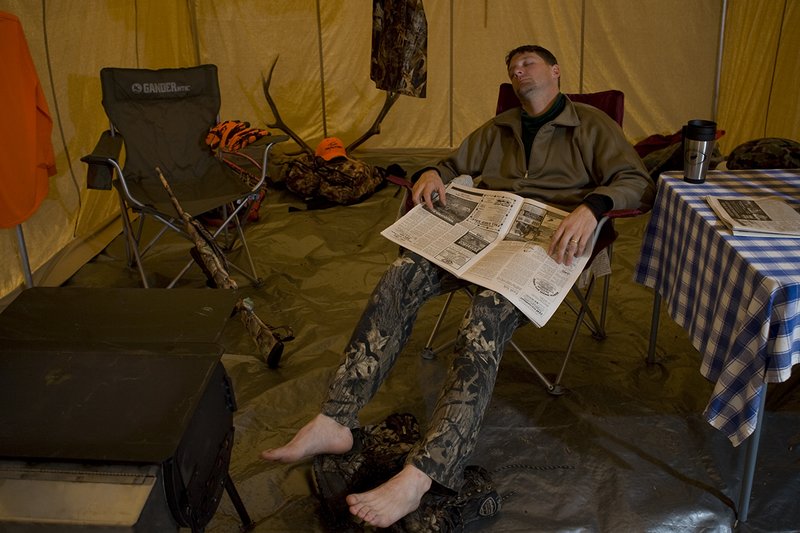 ©TC_Hunting Camps-D80003-156.jpg :: Hunter sitting on chair inside wall tent, getting warm and drying off after a day of hunting elk