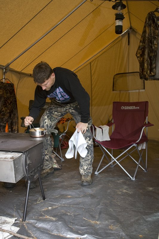 ©TC_Hunting Camps-D80003-159.jpg :: Hunter cooking soup on wood stove inside wall tent, warming up after morning of hunting elk