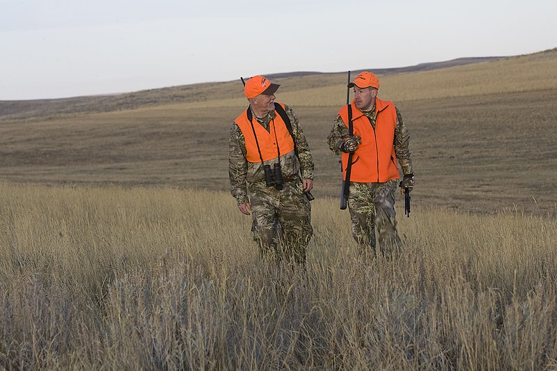 ©TC_Prairie Rifle Hunter-D89991-243.jpg :: Rifle hunter(s) on prairie, wearing Advantage Max-1HD camo, with a florescent orange vest, Bushnell Elite 3x9 Rifle sclope, Elite Binoculars