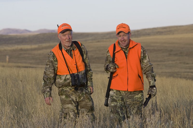 ©TC_Prairie Rifle Hunter-D89991-256.jpg :: Rifle hunter(s) on prairie, wearing Advantage Max-1HD camo, with a florescent orange vest, Bushnell Elite 3x9 Rifle sclope, Elite Binoculars