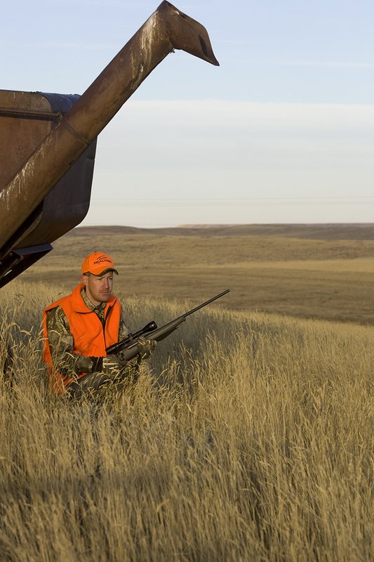 ©TC_Prairie Rifle Hunter-D89991-268.jpg :: Rifle hunter(s) on prairie, wearing Advantage Max-1HD camo, with a florescent orange vest, Bushnell Elite 3x9 Rifle sclope, Elite Binoculars